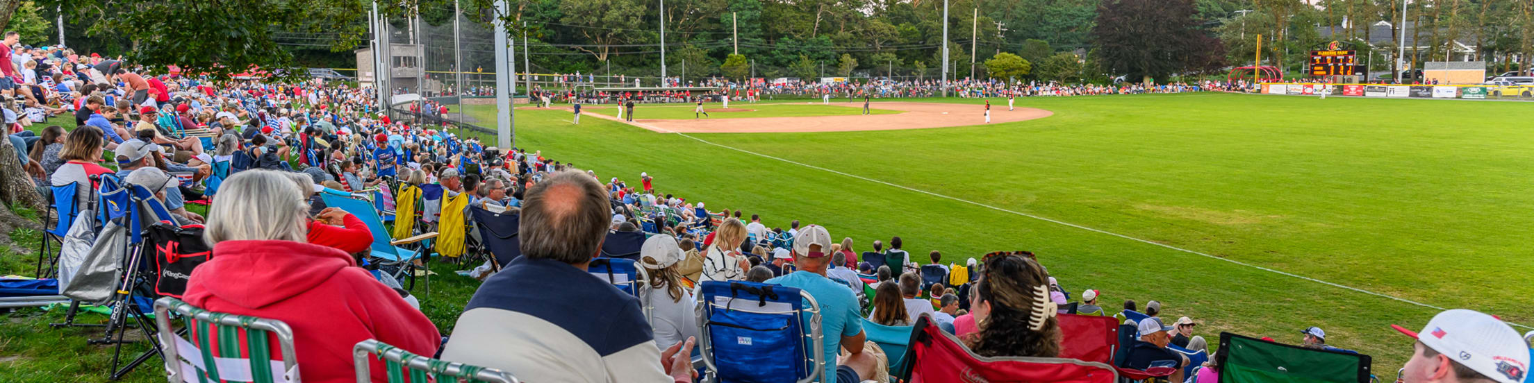 A wide view of Eldredge Park with packed stands during a day game from the right-field corner.