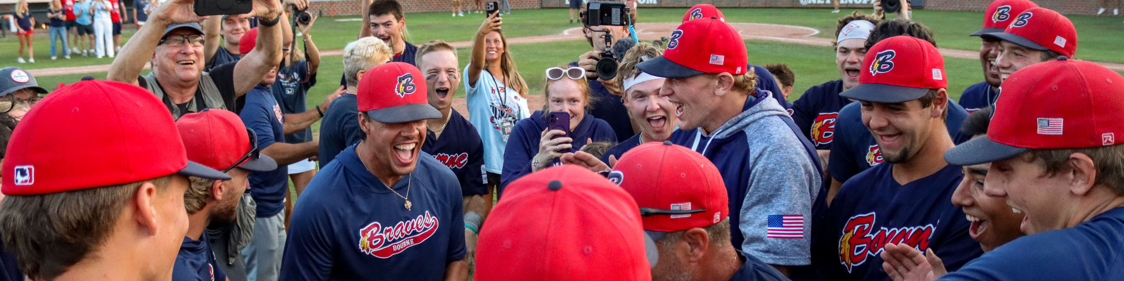 Bourn players celebrate in a team huddle just beyond the pitcher's mound.