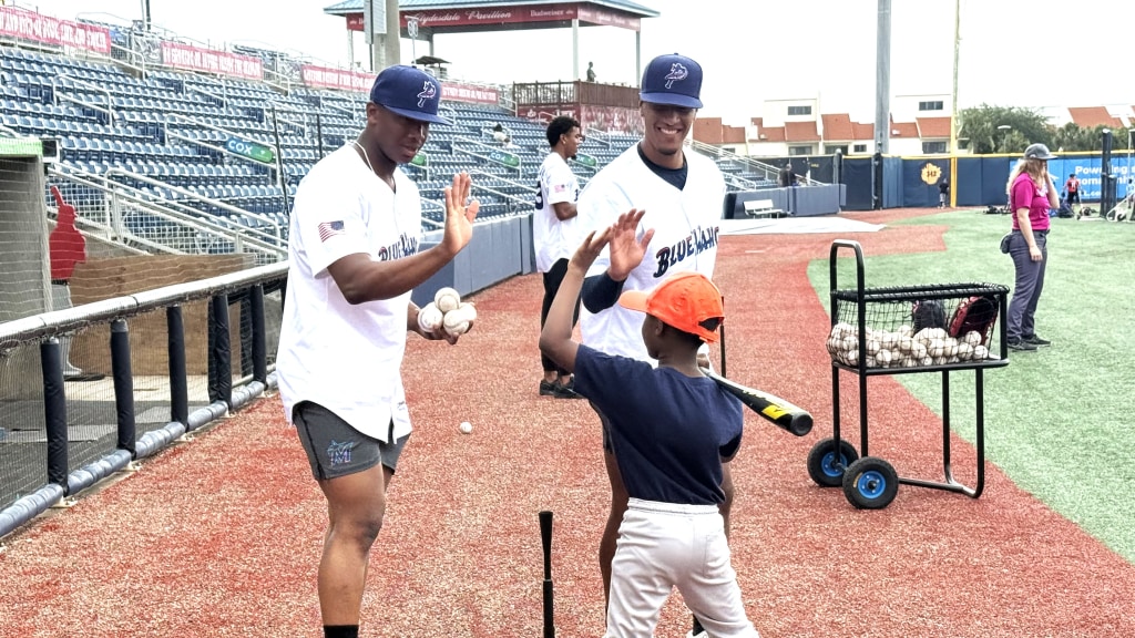 Blue Wahoos pitchers Nigel Belgrave and Elizar Dishmey congratulate a youth participant in the Jun6 6 Blue Wahoos Fred Waters Youth Baseball Clinic at Blue Wahoos Stadium.