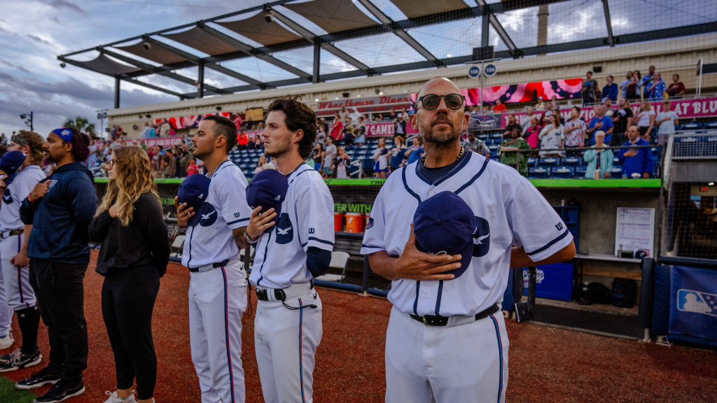 Blue Wahoos manager Nelson Prada, front right, during National Anthem of a rain-delayed game June 19 when team wore Pensacola Seagulls uniforms.