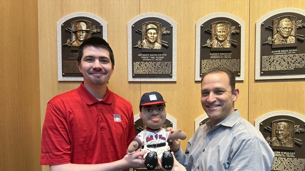 Kourage Kundahl, former Pensacola Pelicans batboy, holds up a special figurine during his role as digital content producer at National Baseball Hall of Fame in Cooperstown.