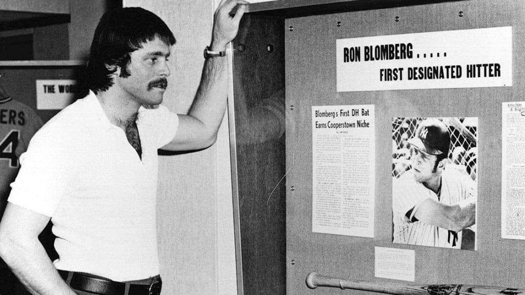 Ron Blomberg looks at the bat he used as the first DH in a display at the Hall of Fame in the 1970s.
