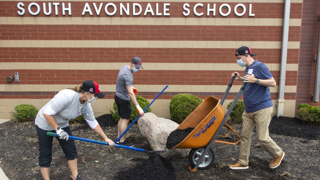 Cincinnati Children’s employees spread mulch outside South Avondale Elementary.