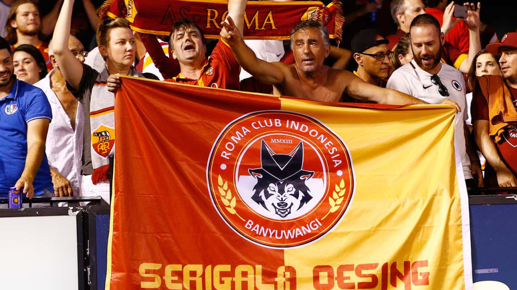 Fans hold an AS Roma flag during the soccer friendly against Liverpool on Monday. AS Roma won the match, 2-1.