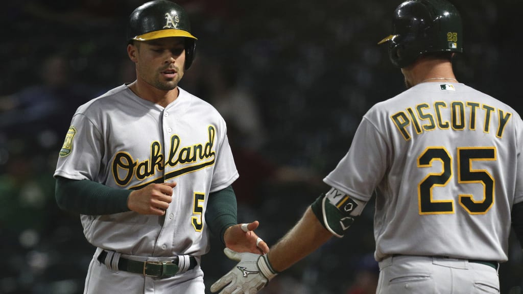 Oakland Athletics Jake Smolinski (5) is greeted by Stephen Piscotty (25) after scoring on a single by Jonathan Lucroy in the ninth inning of a baseball game against the Texas Rangers Monday, April 23, 2018, in Arlington, Texas. (AP Photo/Richard W. Rodriguez)