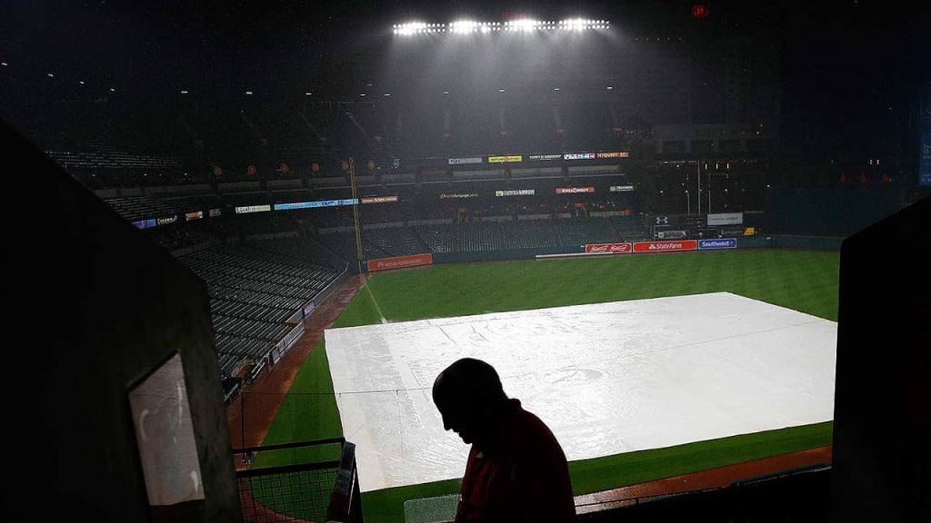 Fans took cover as rain fell on the tarp-covered field at Camden Yards on Tuesday night. (AP)