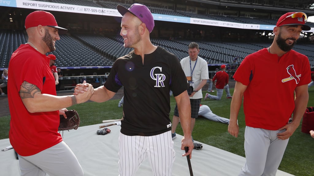 From left, St. Louis Cardinals first baseman Matt Adams greets Colorado Rockies left fielder Matt Holliday as Cardinals first baseman Matt Carpenter looks on as the teams warm up before a baseball game Friday, Aug. 24, 2018, in Denver. (AP Photo/David Zalubowski)