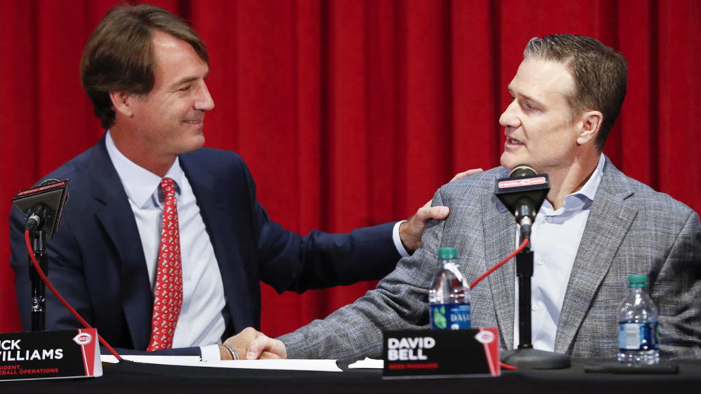 Cincinnati Reds manager David Bell, right, shakes hands with Dick Williams, president of baseball operations, left, Monday, Oct. 22, 2018, in Cincinnati. Bell has been hired as manager of the Cincinnati Reds, tasked with helping turn around a team that skidded to a 67-95 record and last-place finish in the NL Central. The Reds said Sunday, Oct. 21, 2018, he has been given a three-year contract that includes a team option for 2022. (AP Photo/John Minchillo)