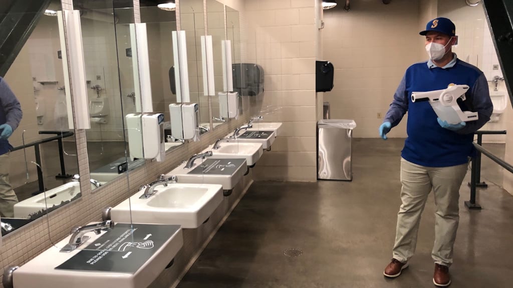 A Mariners staffer displays an electrostatic sprayer that will apply an electrically charged, broad-spectrum disinfecting solution on the surface areas in bathrooms.