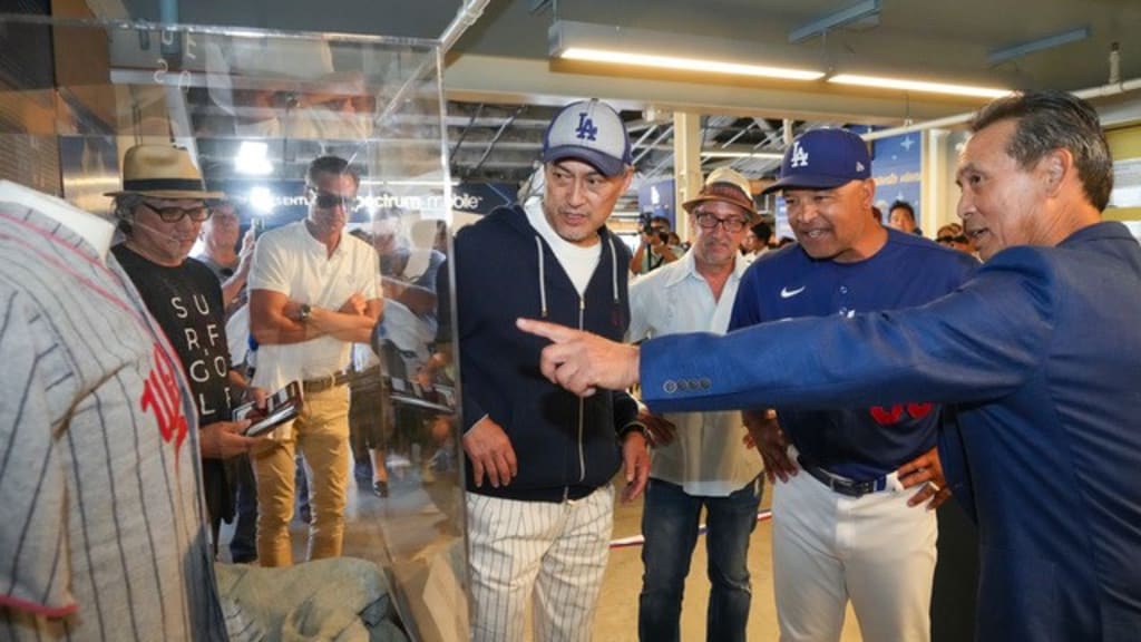 Actor Ken Watanabe and Dodgers manager Dave Roberts receive a tour of the exhibit "Baseball’s Bridge to the Pacific: Celebrating the Legacy of Japanese American Baseball" from its founding curator, Kerry Yo Nakagawa.