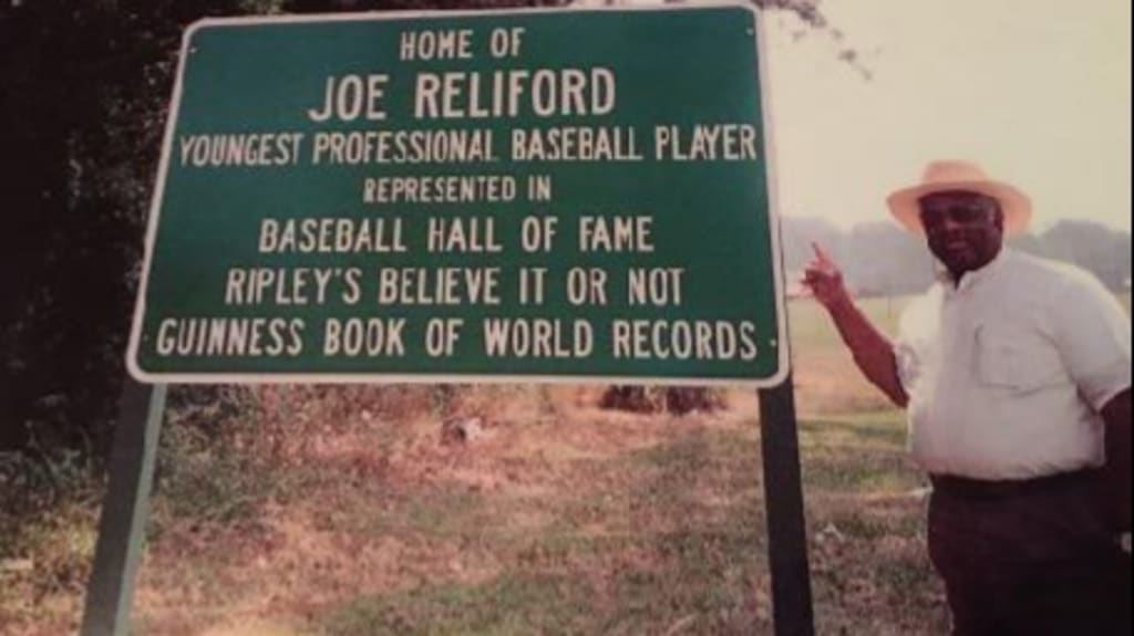 Reliford poses with a Douglas, GA., sign honoring his moment back in 1952