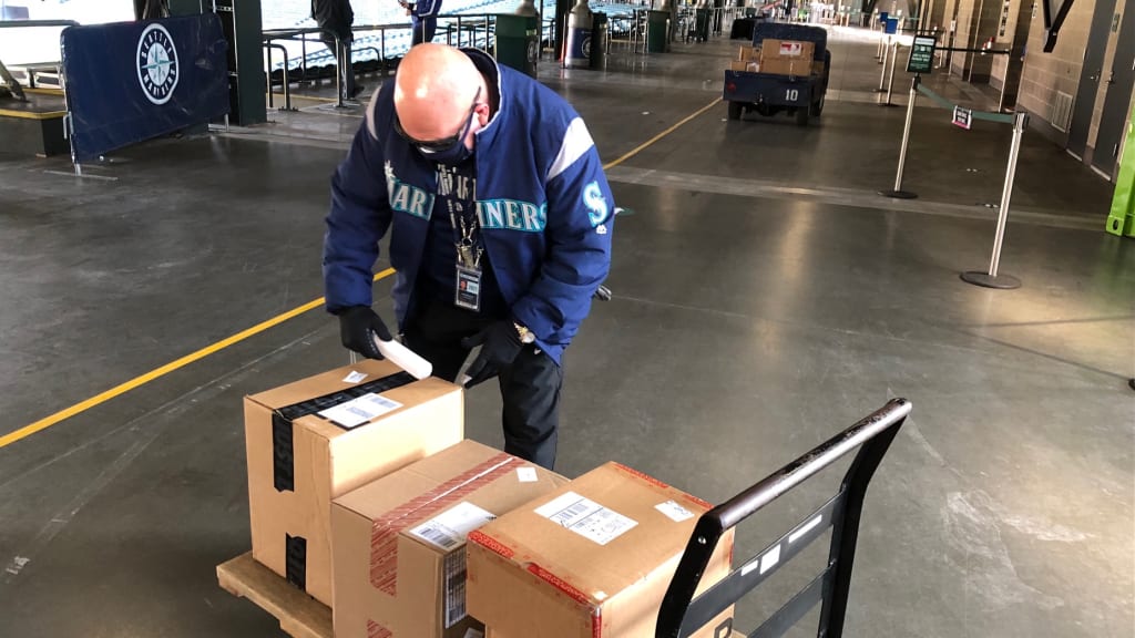 On incoming packages for players, a Mariners staffer applies Glo Germ, an evidence-based surface disinfection and cleaning verification program that uses fluorescent markers to detect the presence of biological contaminants and pathogens.