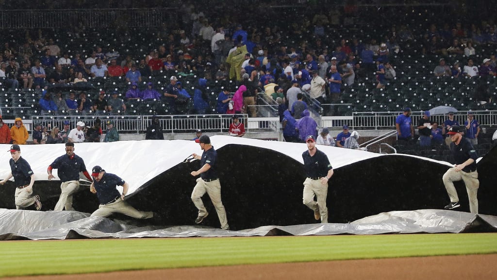 Members of the Atlanta Braves grounds crew rush to cover the infield during a rain shower before the Braves' baseball game against the Chicago Cubs on Thursday, May 17, 2018, in Atlanta. (AP Photo/John Bazemore)