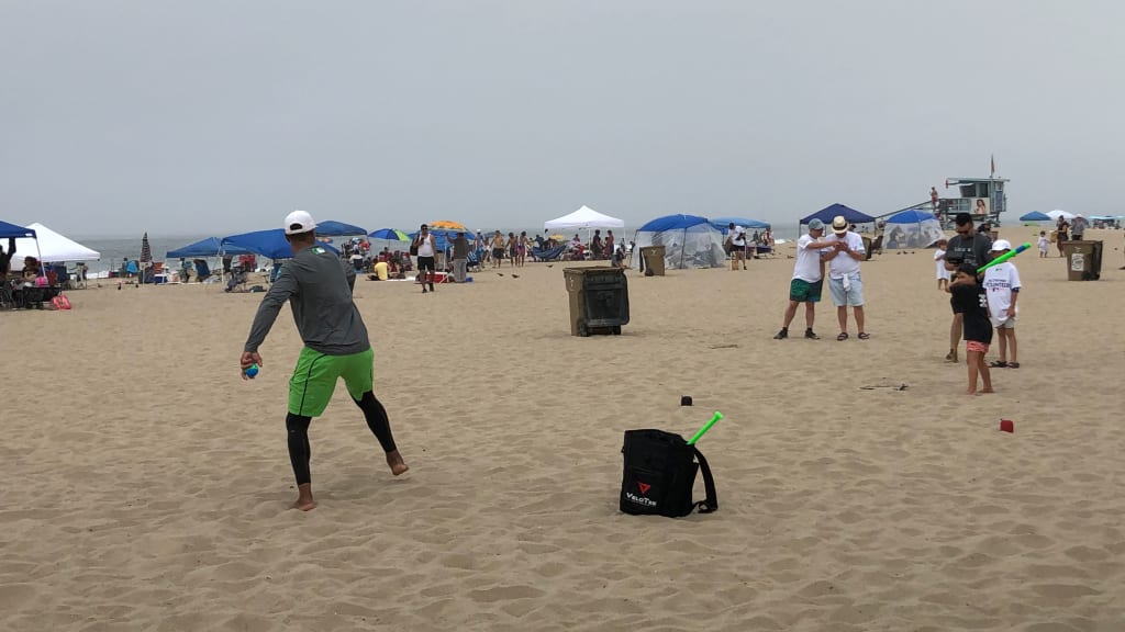 Chris Dickerson pitches to a young fan at MLB, Heal the Bay and Players for the Planet's All-Star Beach Cleanup on Saturday, July 16, 2022.