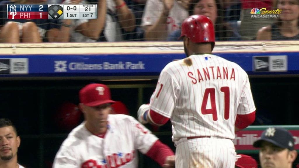 Philadelphia Phillies - Rhys Hoskins, wearing the cream Phillies uniform,  celebrating with the dugout after scoring a run.