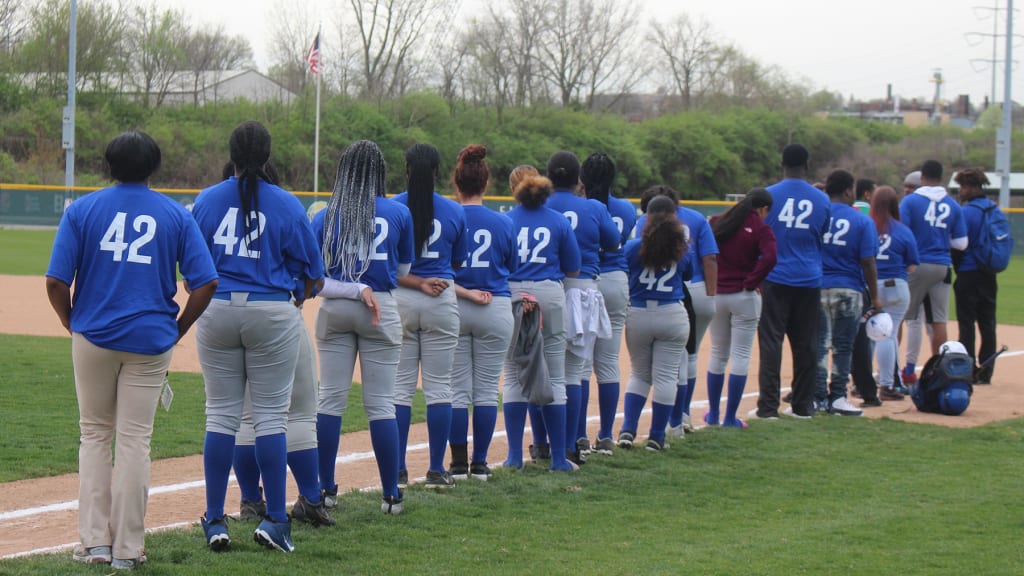 Members of the Woodward High School softball team wear the '42' jerseys and line up for the national anthem prior to their game against Shroder on Jackie Robinson Day at the Reds Youth Academy. The jerseys were underwritten by the Reds Community Fund.