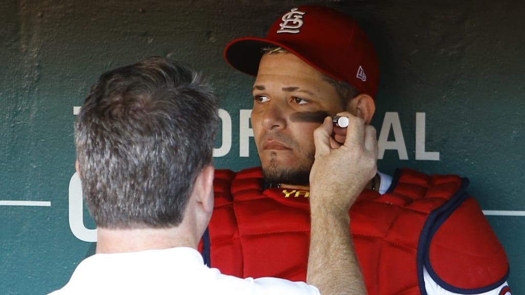 A trainer applies eyeblack to St. Louis Cardinals catcher Yadier