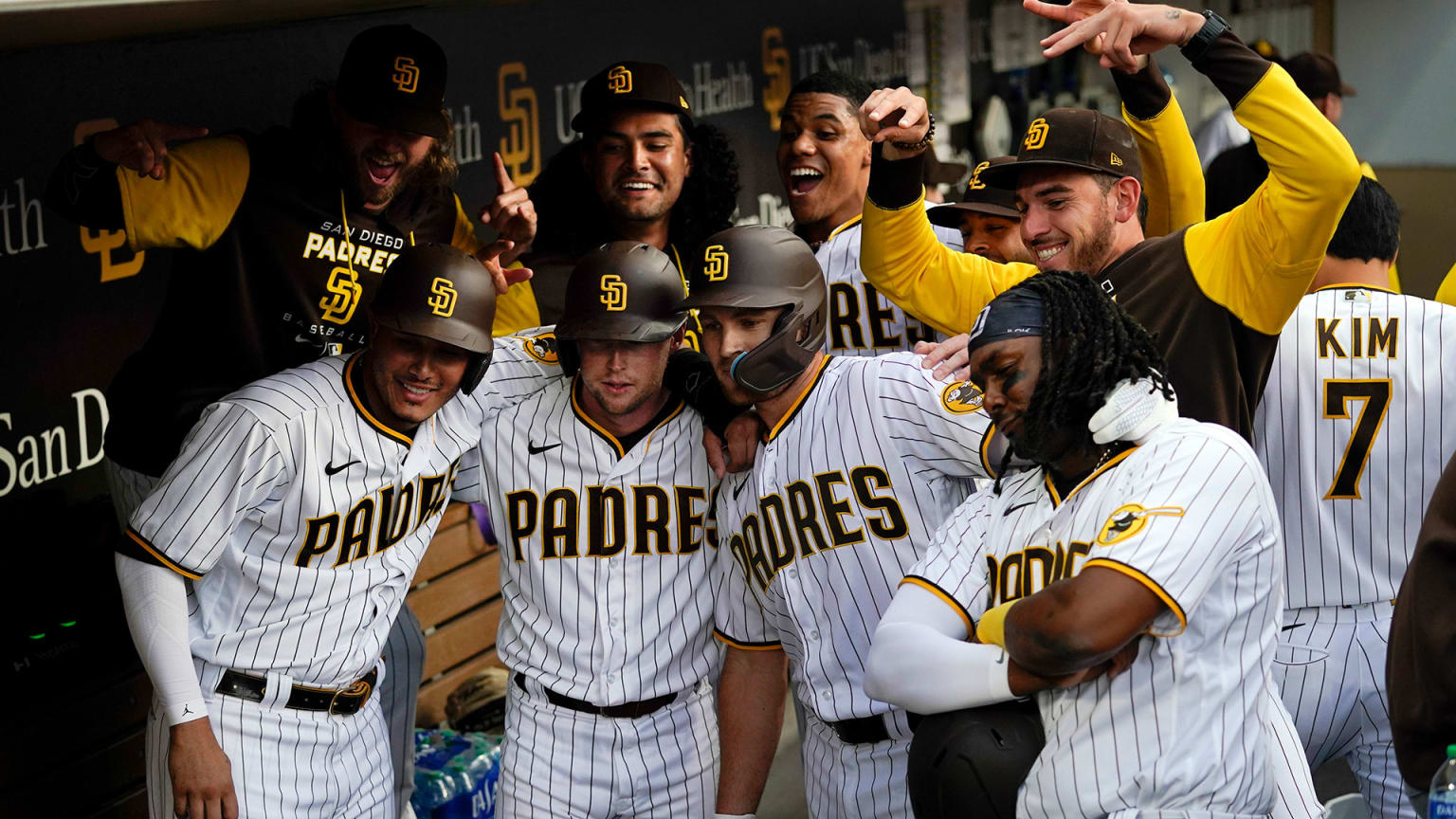 Eight Padres players gather in the dugout pretending to pose for a photograph