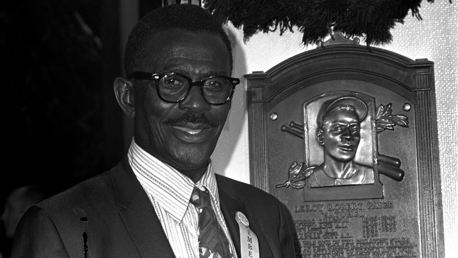 A black-and-white image of Satchel Paige standing next to his plaque