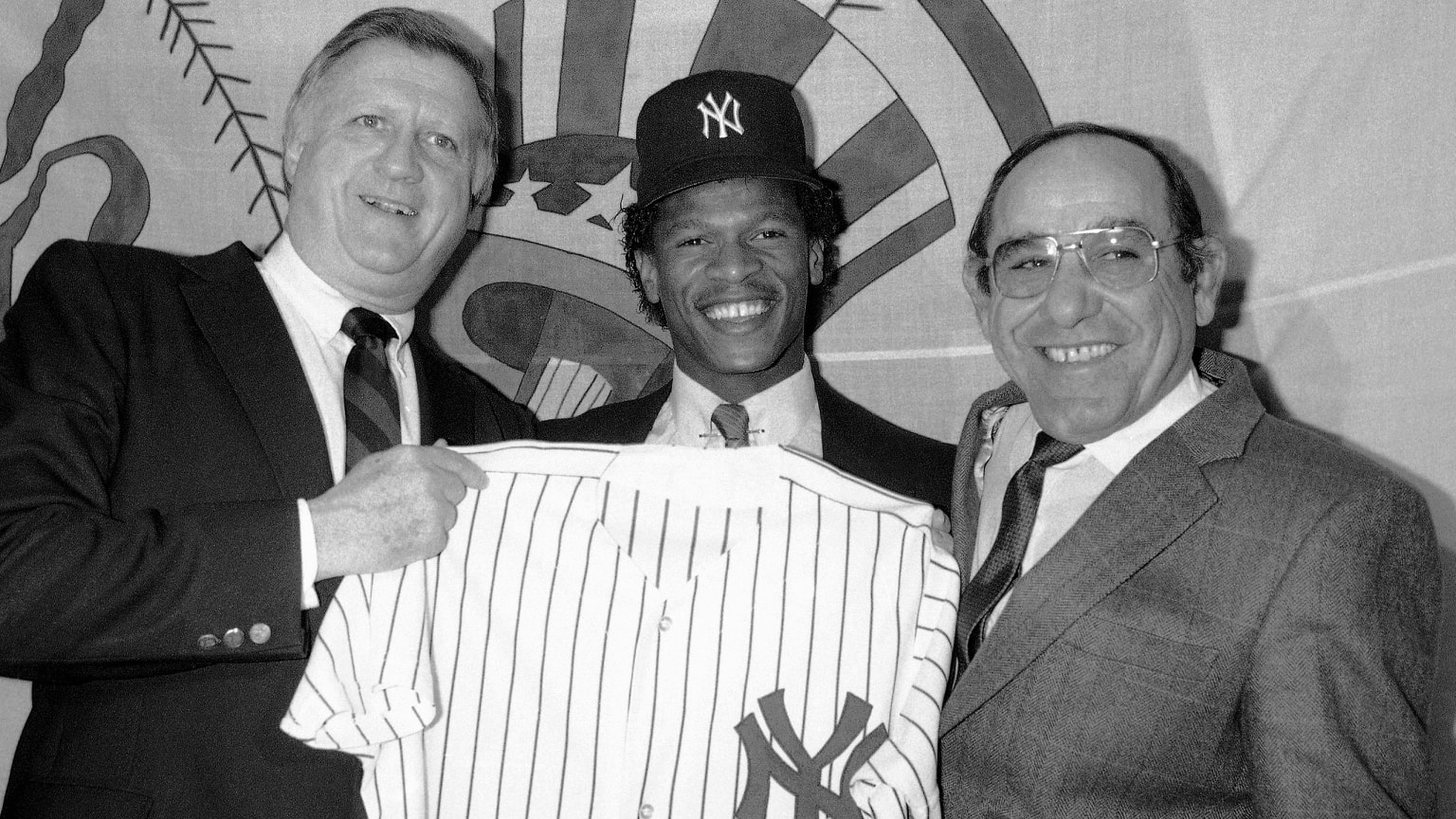 George Steinbrenner, Rickey Henderson and Yogi Berra pose with a Yankees jersey