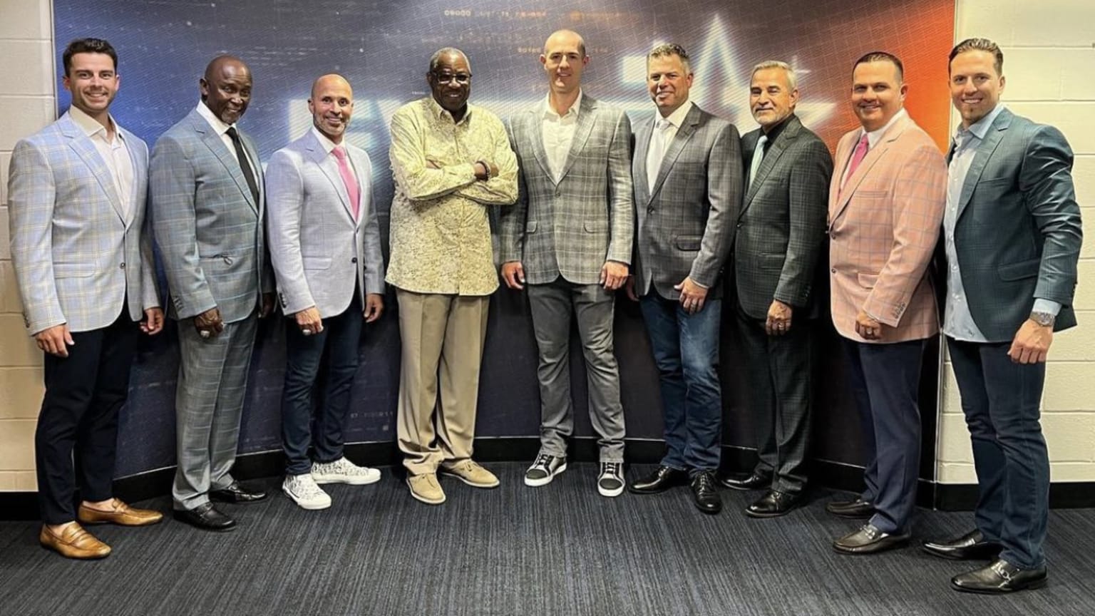 Nine coaches in suits stand in a semi-circle