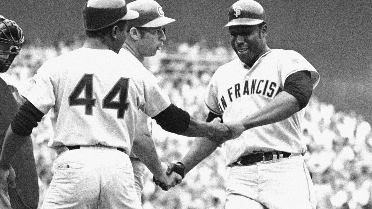 A black-and-white photo of Willie McCovey being greeted at home plate