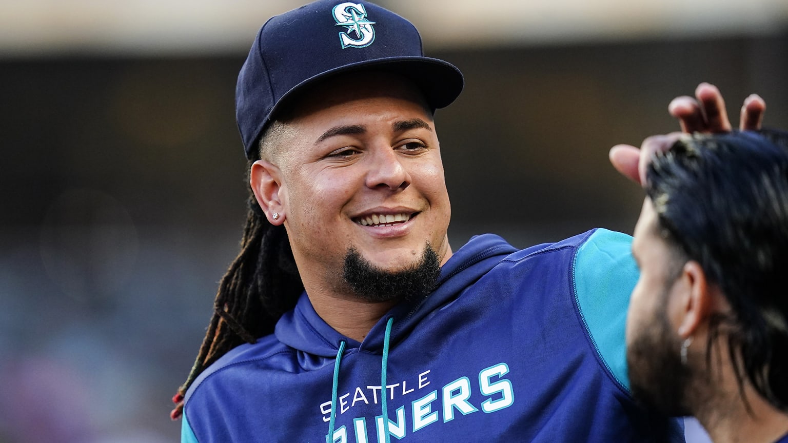 Luis Castillo smiles while interacting with a Mariners teammate