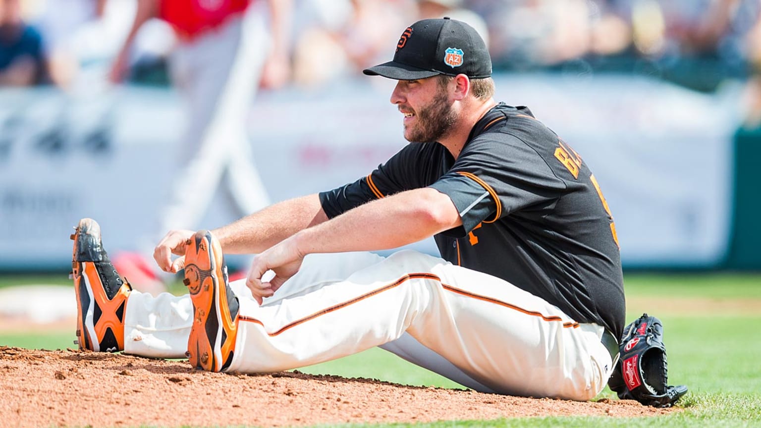 A player reaches for his feet while sitting on the mound