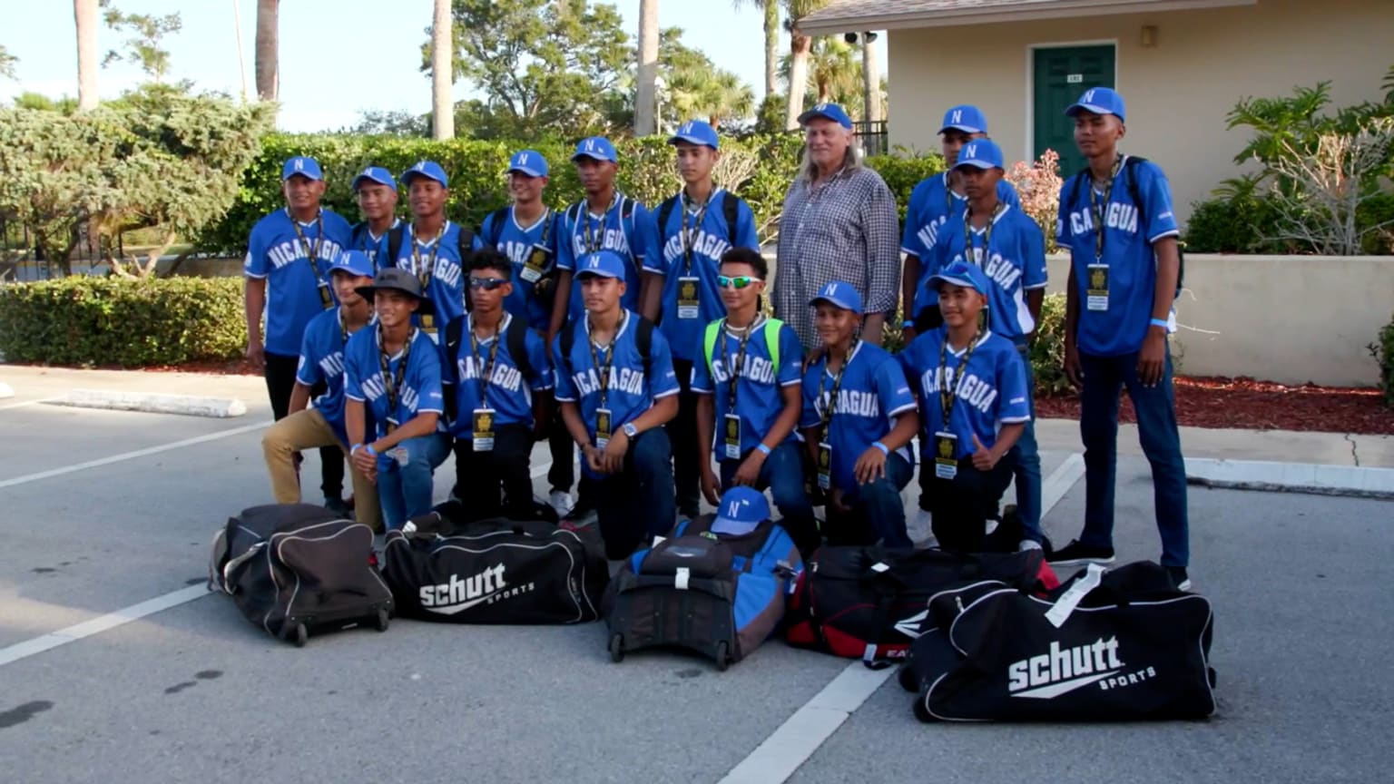 A team of boys in blue uniforms poses for a picture in a parking lot