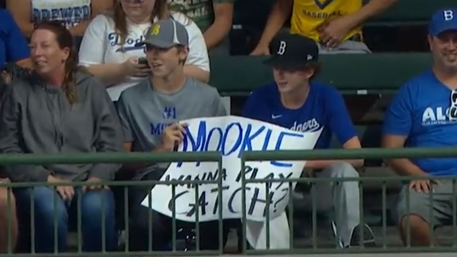 Two fans hold a sign reading, ''MOOKIE WANNA PLAY CATCH?''