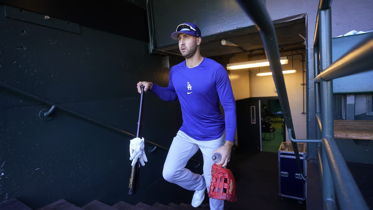 Joey Gallo wears a Dodgers shirt and carries a bat and glove as he emerges from the clubhouse