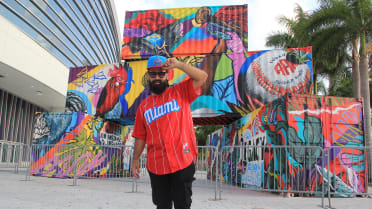 Fans take photographs next to a sculpture by Puerto Rican artist Carlitos  Skills, titled Folklore, in celebration of the Cuban Sugar Kings baseball  team, outside loanDepot Park before a baseball game between