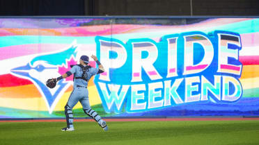 People hold a pride themed Toronto Blue Jays flag to celebrate Pride Weekend  before the Blue