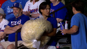 HUGE bag of popcorn coexists with Rangers fan at game