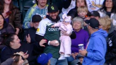 Rockies fan catches ball while holding their baby