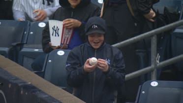 A young Yankees fan receives a ball from Juan Soto