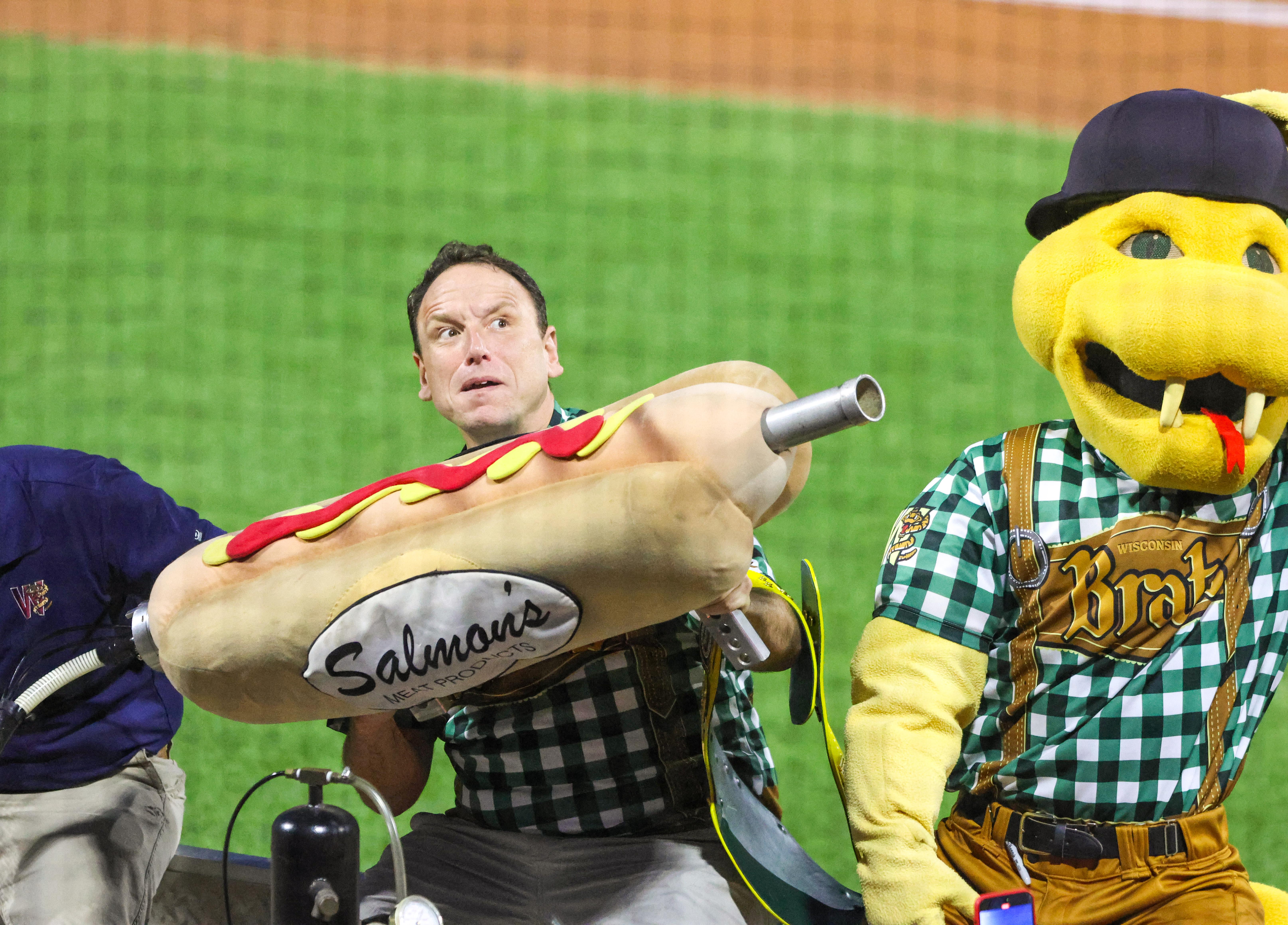 Joey Chestnut fires the Bratzooka as mascot Fang looks on.