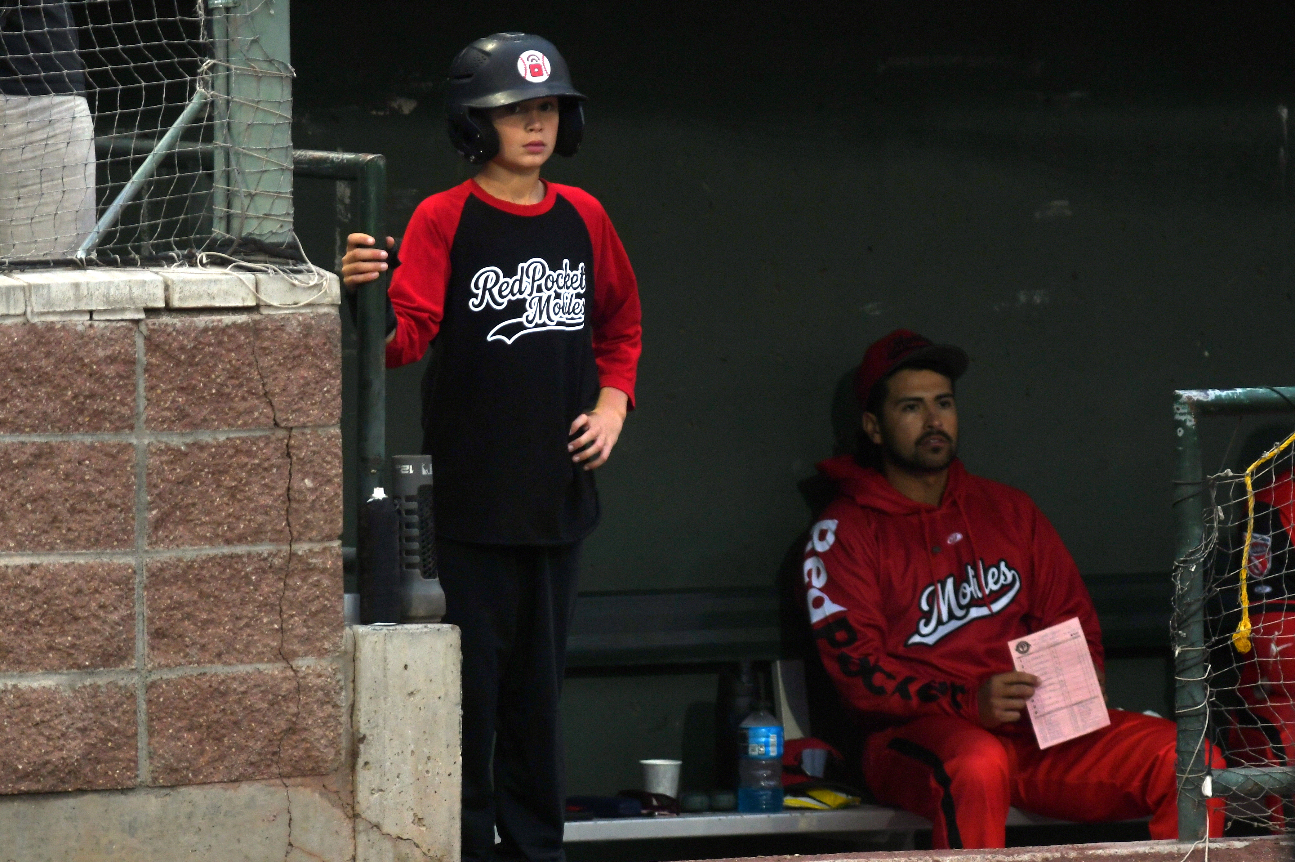 A bat boy watches the game from the dugout. Photo courtesy the RedPocket Mobiles.