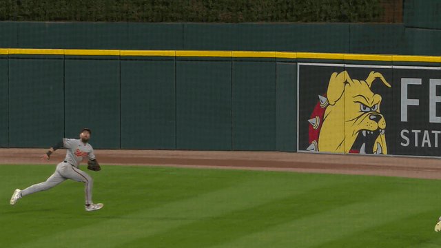 An animated gif of Colton Cowser making a diving catch and sliding on his back across the outfield grass