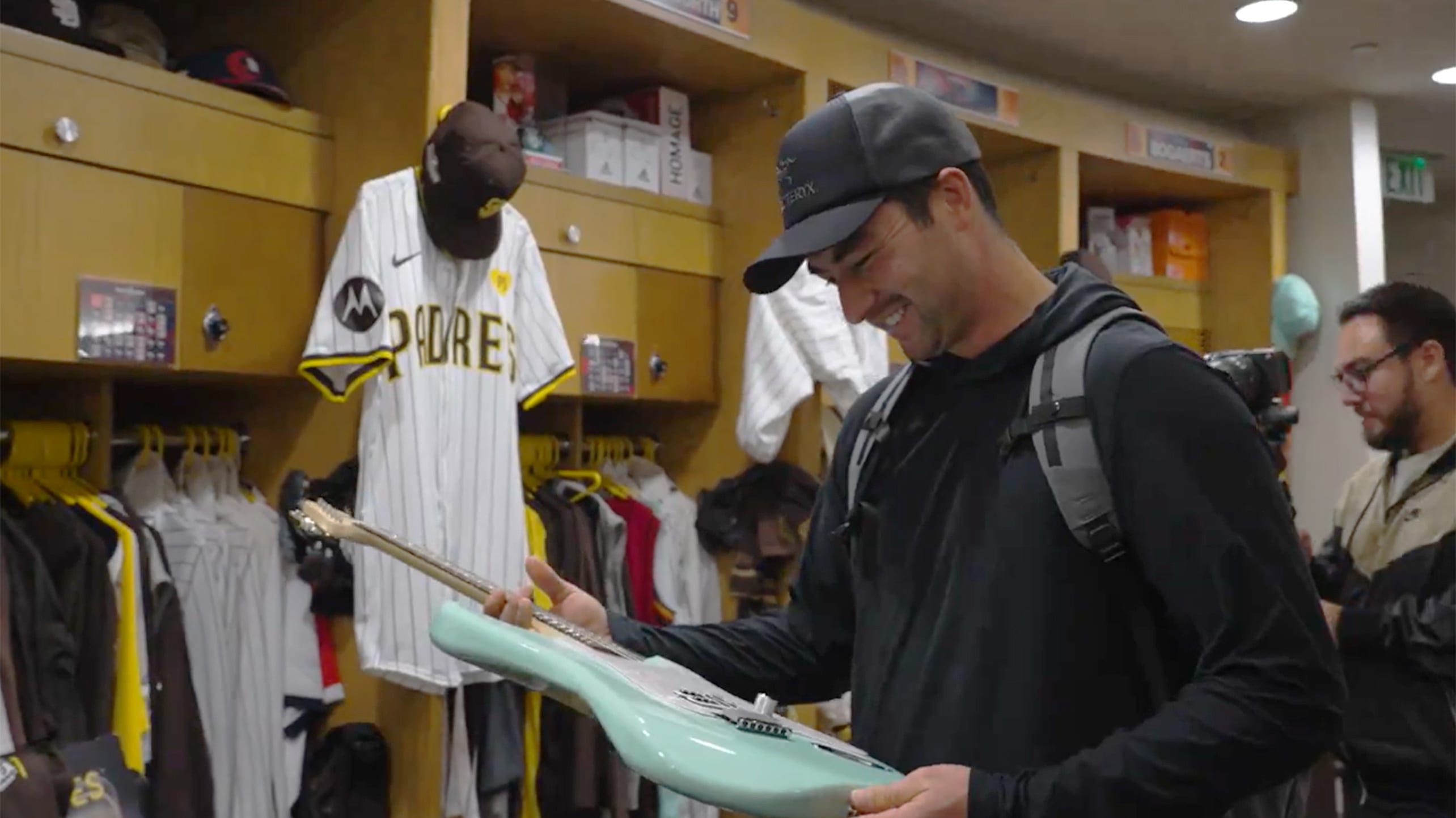 Padres catcher Kyle Higashioka admires a guitar gifted to him by blink-182's Tom DeLonge