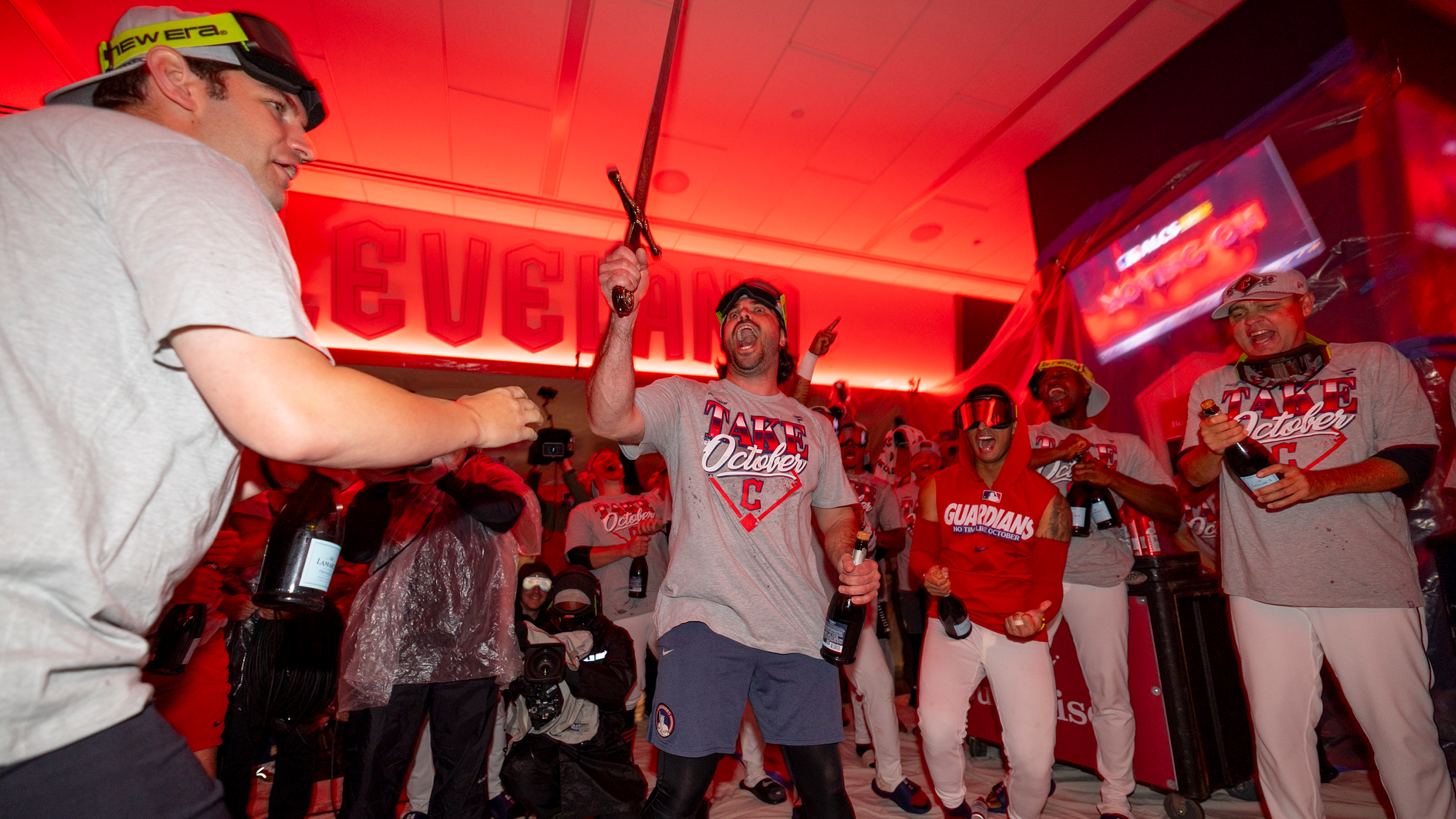 Austin Hedges holds up a sword while the Guardians celebrate in the clubhouse
