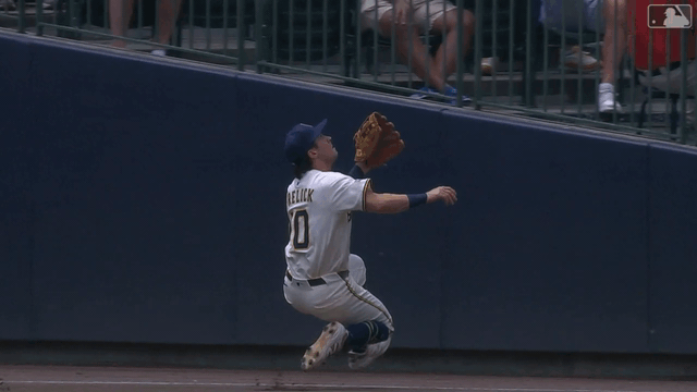 An animated gif of the Brewers' Sal Frelick making a sliding catch before bumping into the wall in foul territory