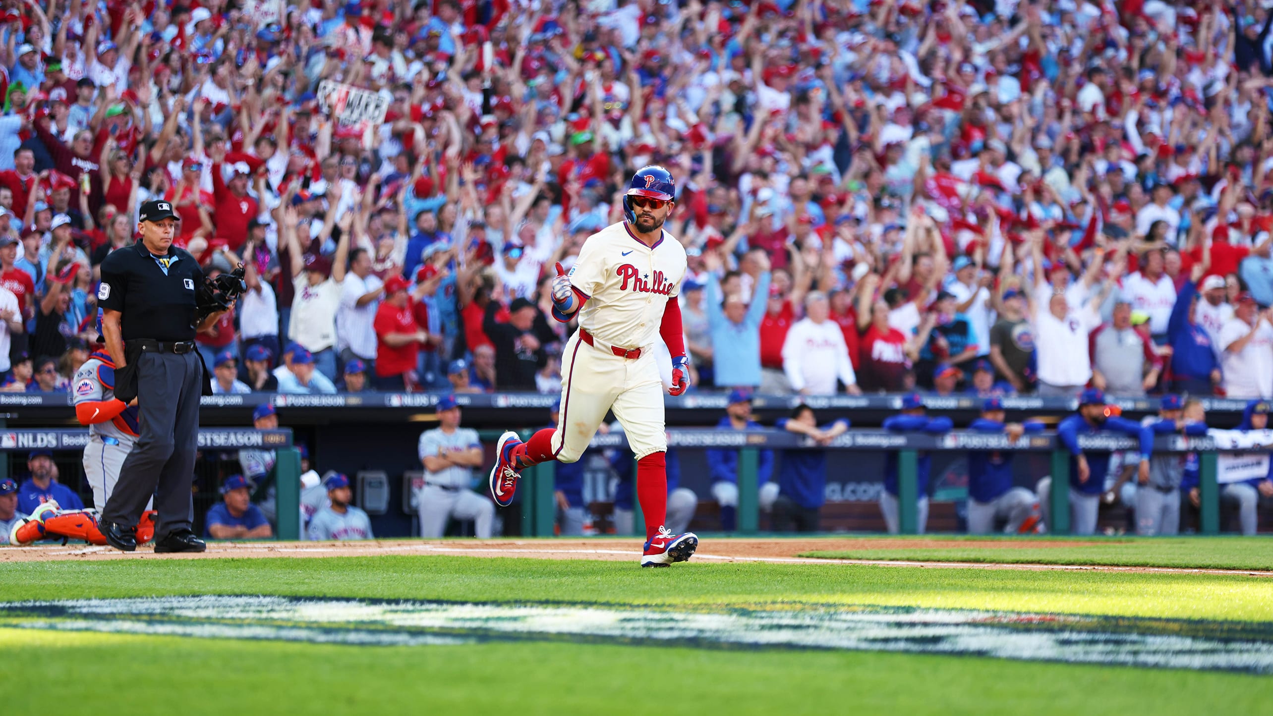 Kyle Schwarber gives a thumbs up to the dugout as he trots to first after hitting a leadoff home run