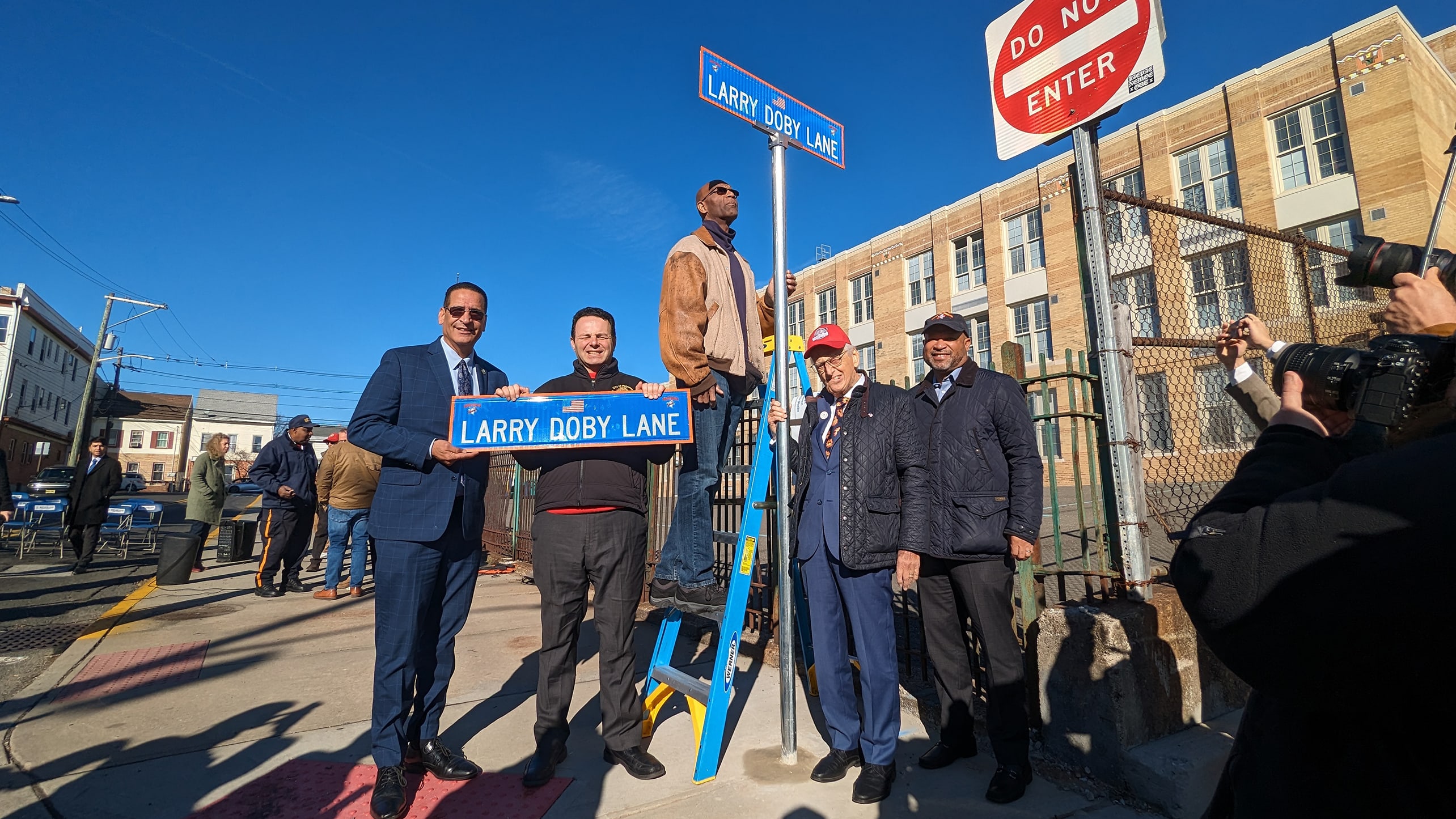 Five men pose beneath a street sign at Larry Doby Lane