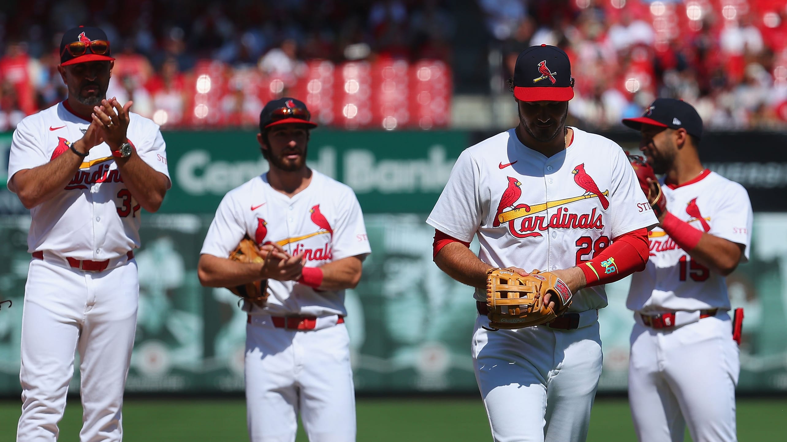 Cardinals manager Oliver Marmol and two Cardinals teammates applauding Nolan Arenado as he leaves the field