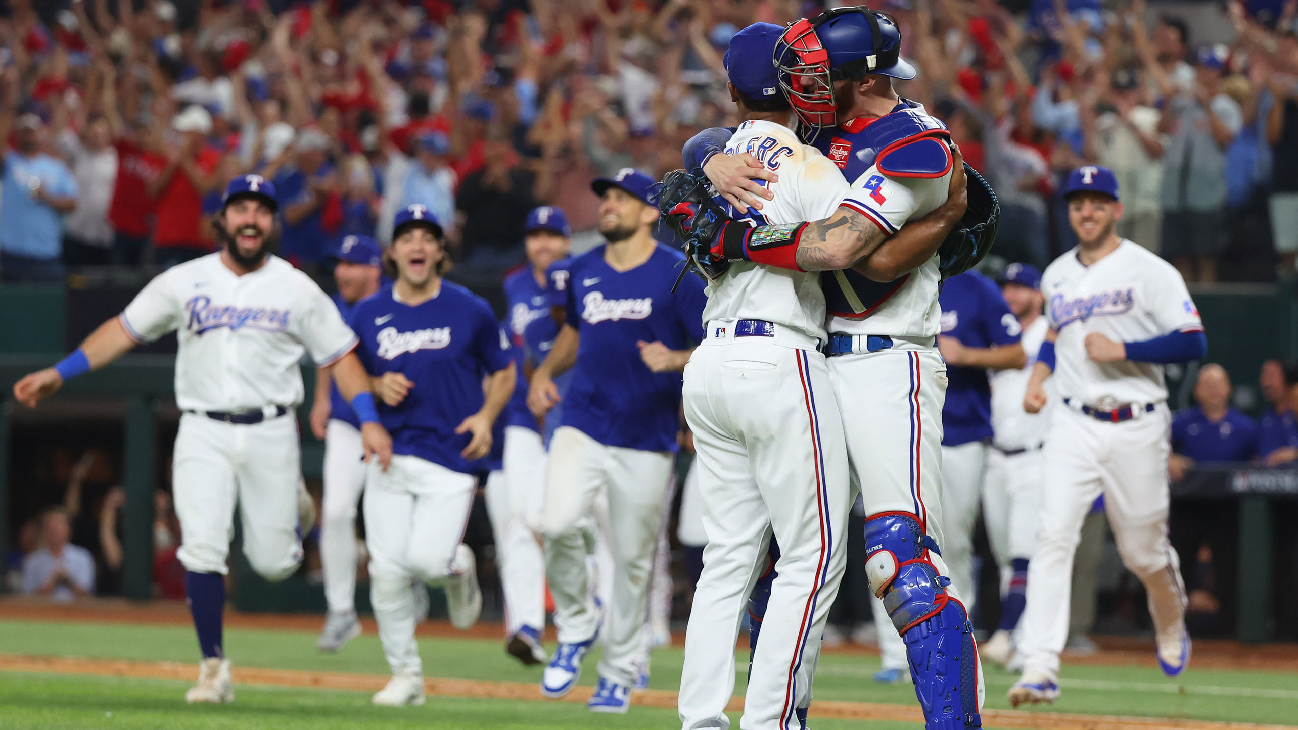 Pitcher Jose Leclerc and catcher Jonah Heim hug as the Rangers rush out from their dugout