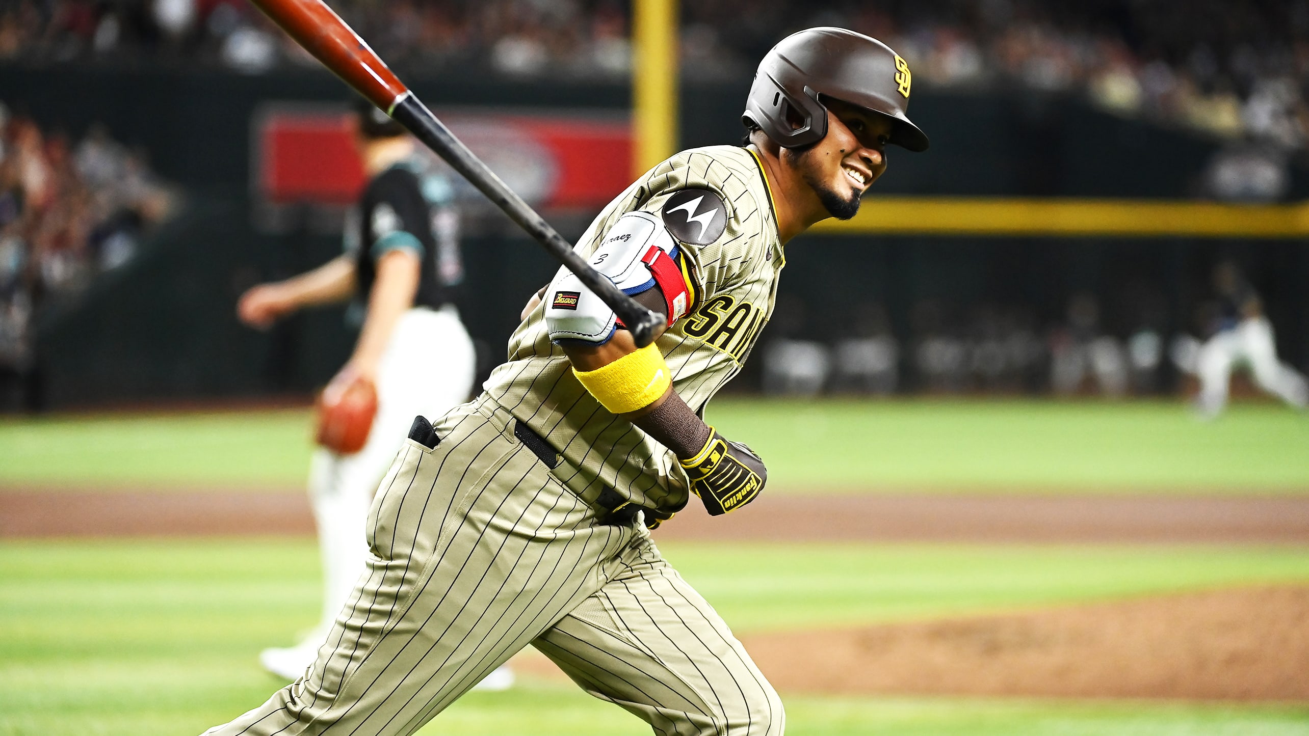 Luis Arraez smiles and flips his bat as he runs toward first base