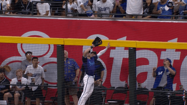 An animated gif of Corbin Carroll reaching high over the wall to rob a home run