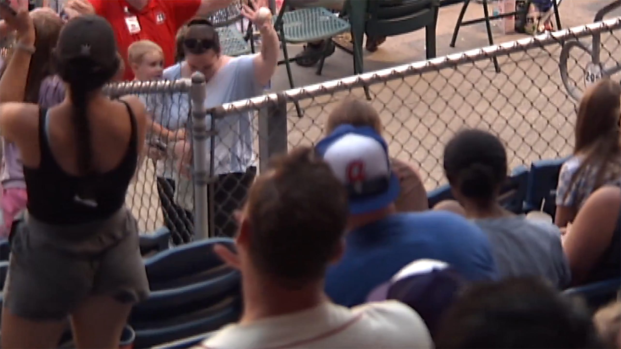 A mother with a child in her arm holds up a foul ball