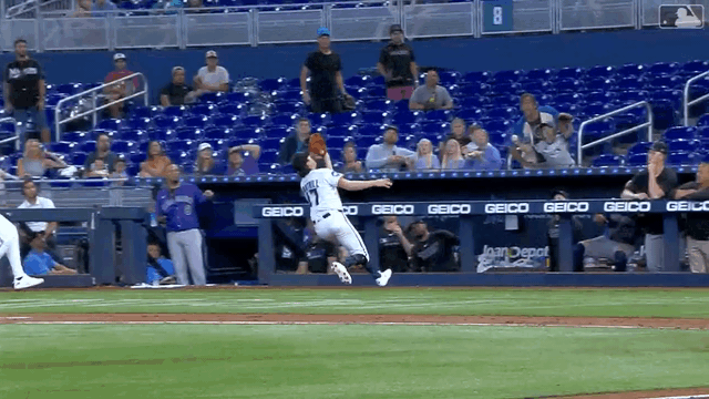An animated gif of Cal Quantrill sliding into the dugout fence and making a catch